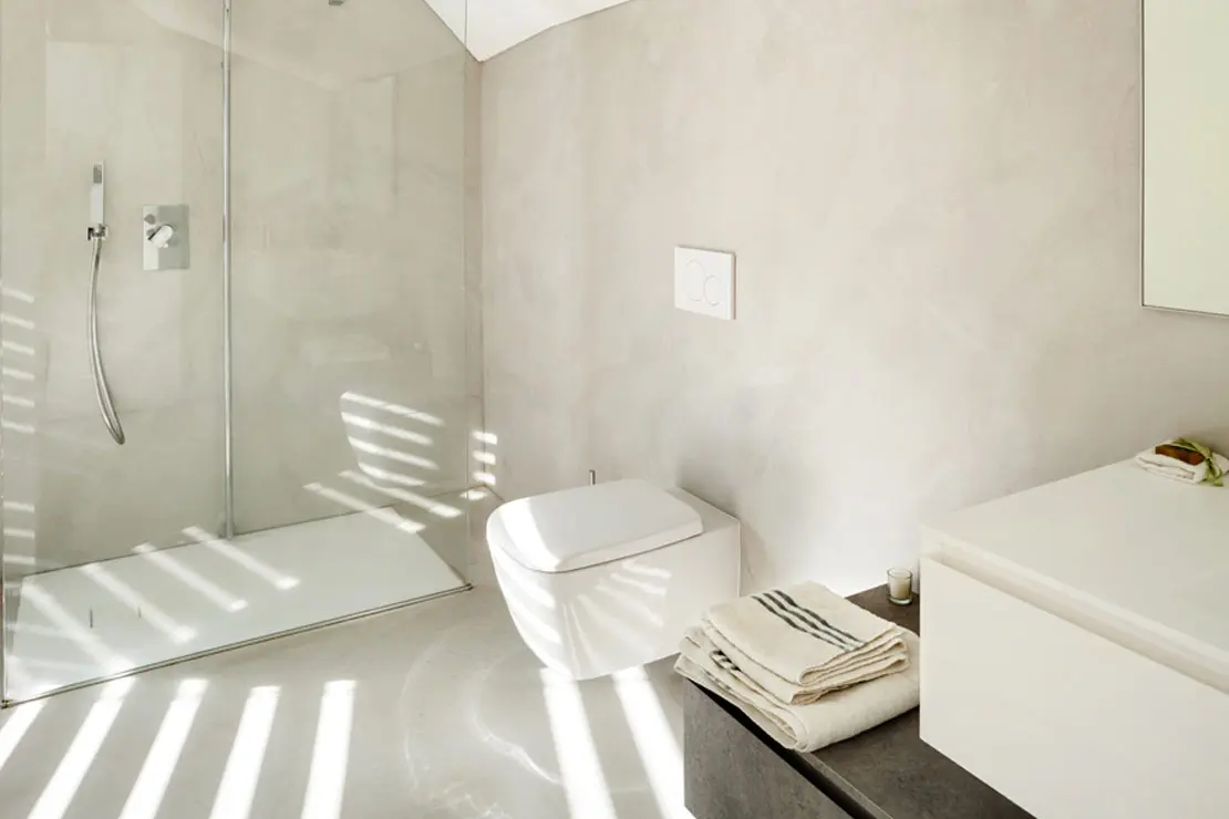 Baño con piso y muros de microcemento en tono luminoso